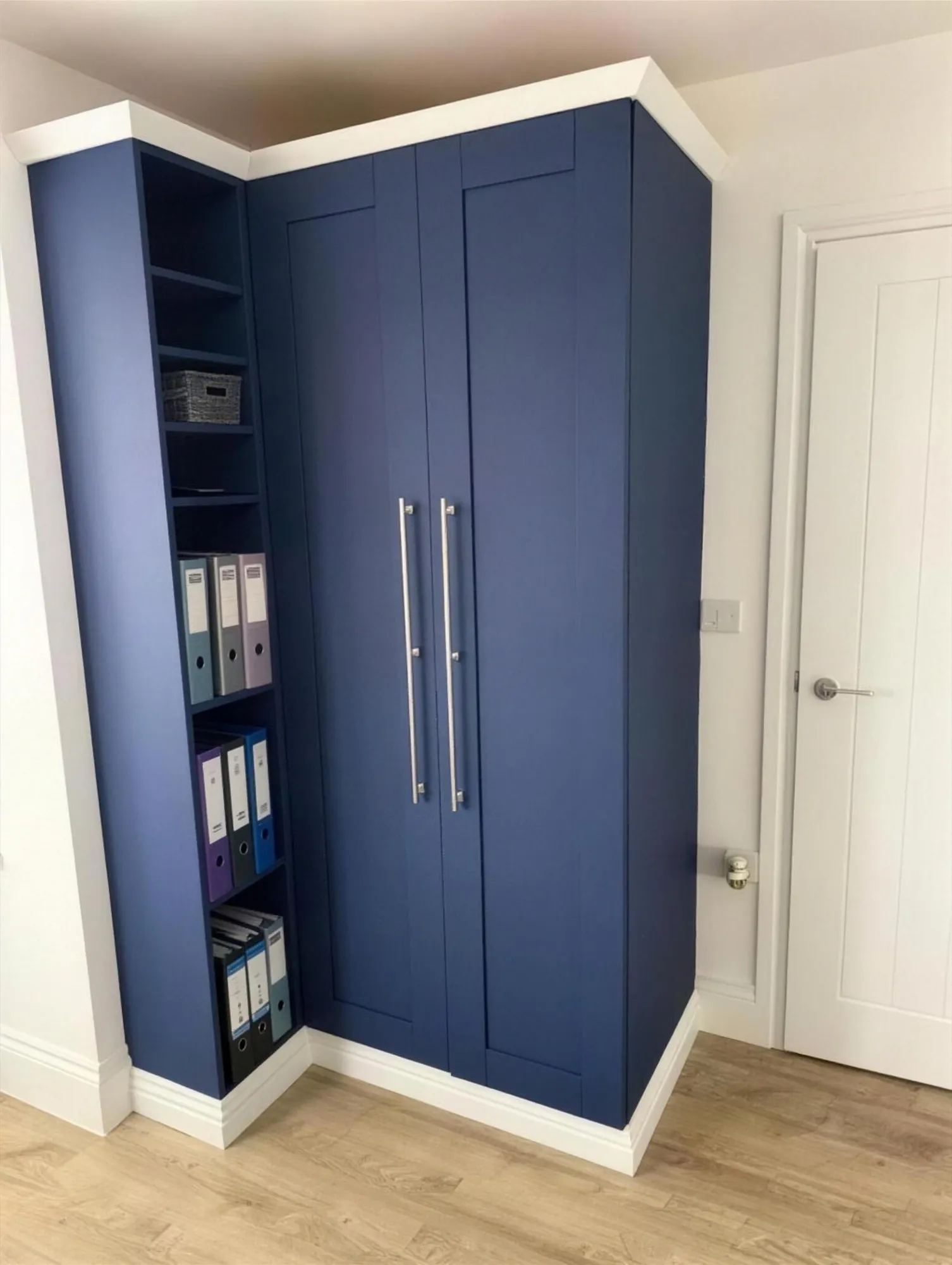 Built-in navy blue wardrobe with open shelving fitted into an alcove